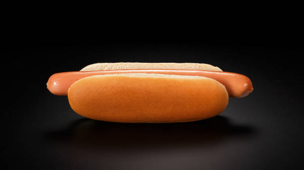 Simple hot dog (sausage with a bun) on a black background. stock photo