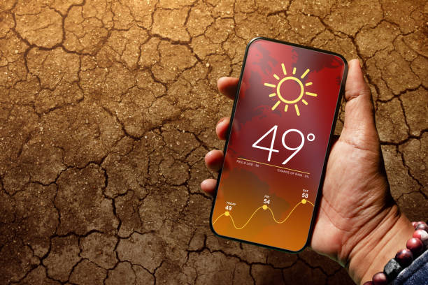 istock Ecology and Technology Concept. High Temperature Weather show on Mobile Screen on Hot Sunny Day. Top View, Dry Cracked Earth with Hard Sunlight as background 1191358515