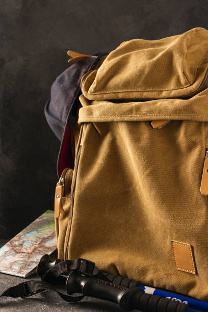 istock Hiking in the mountains concept. Hipster backpack with map and walking poles on dark background 1191359704