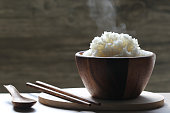 cooked rice in wood bowl with smoke rising on dark background