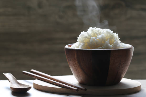 arroz cozinhado na bacia de madeira com fumo que levanta-se no fundo escuro - boiled - fotografias e filmes do acervo