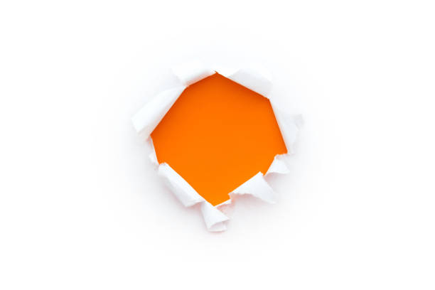 istock A round hole in white paper with torn edges isolated on a white background with a bright orange color paper background inside. 1191363972