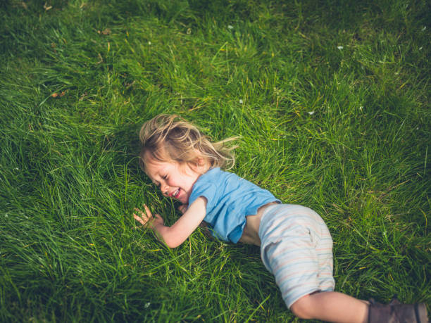 A little toddler is rolling in the grass