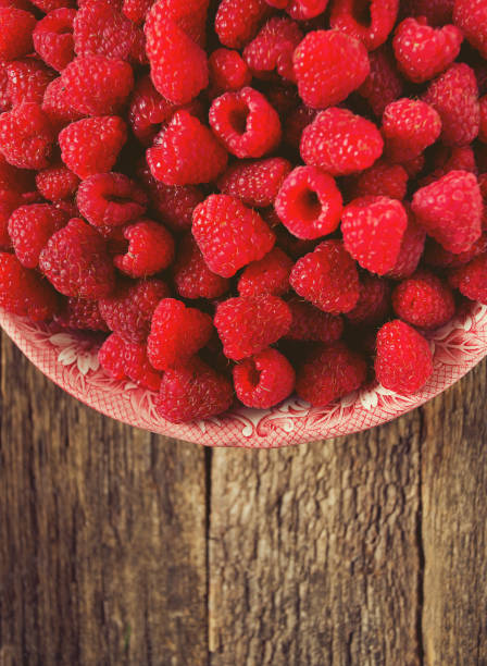 istock full bowl of raspberries on wooden surface 1191368841