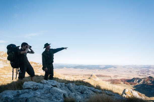 joven y guía usan binoculares en las montañas - light guide fotografías e imágenes de stock