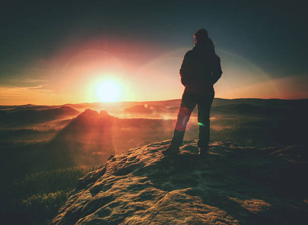 istock Young man walks on hill above mist. Strong daybreak sun 1191376144