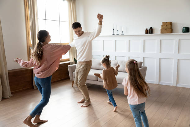 divertenti genitori attivi e figli figlie che ballano in soggiorno - celebration sport caucasian ethnic foto e immagini stock