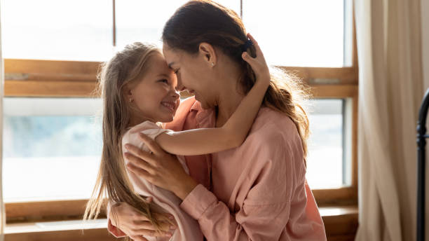 istock Affectionate mom and small daughter embracing bonding in sunny bedroom 1191377630