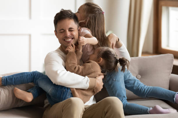 istock Happy father and cute little daughters playing together on sofa 1191377647