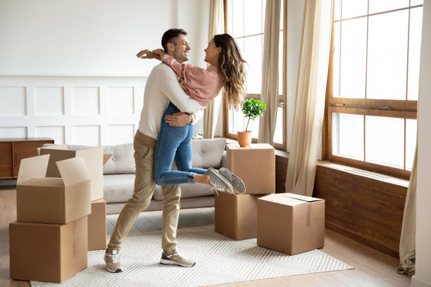 Happy husband lifting excited wife celebrating moving day with boxes Happy young husband lifting excited wife celebrating moving day with cardboard boxes, proud overjoyed family couple first time home buyers renters owners having fun enjoy relocation, mortgage concept unpacking photos stock pictures, royalty-free photos & images