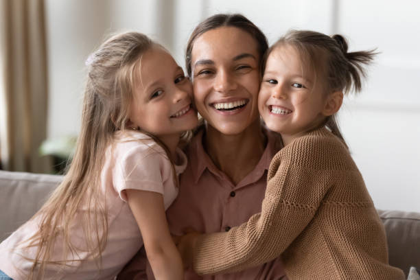 istock Happy mother and children daughters embracing looking at camera 1191377825