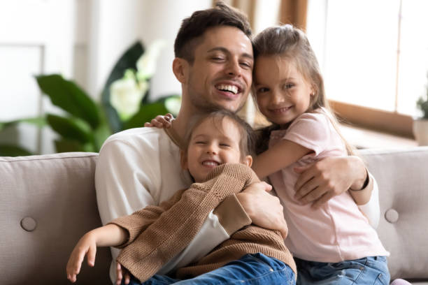 istock Caring daddy and cute children girls bonding hugging on sofa 1191377869