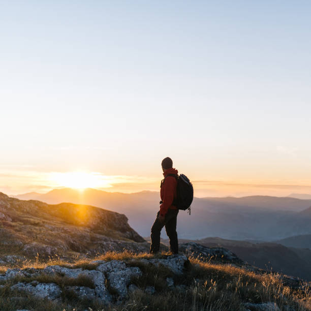 Hiker relaxes above mountain valley at sunrise