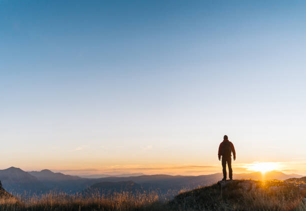 istock Hiker relaxes above mountain valley at sunrise 1191381243