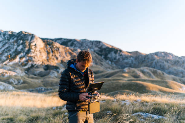 Young man operates drone on mountain ridge