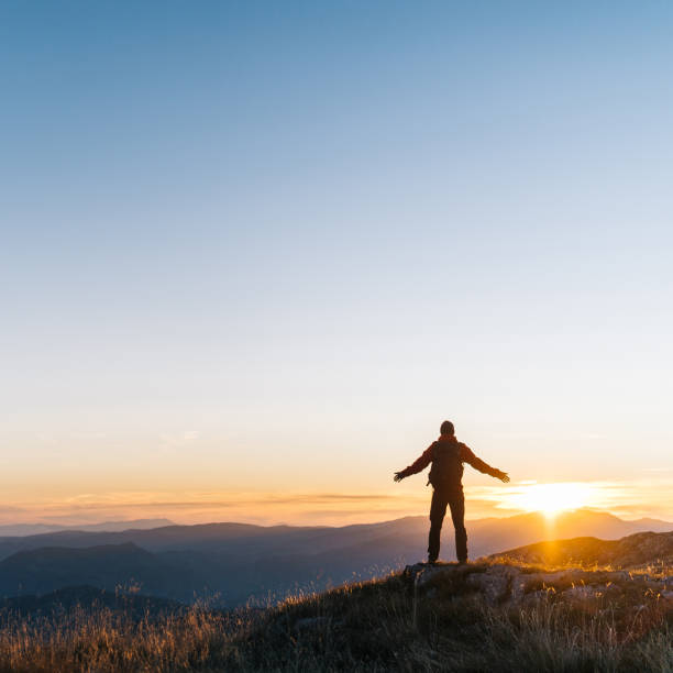 Hiker relaxes above mountain valley at sunrise
