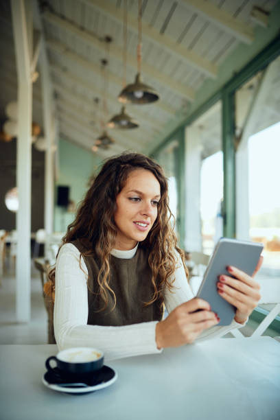 istock Attractive young curly brunette looking at her tablet and smiling 1191384333