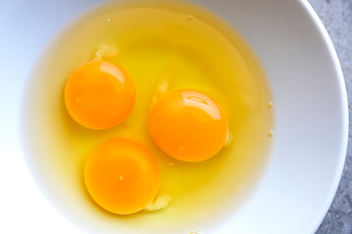 Raw organic egg yolk in white bowl background