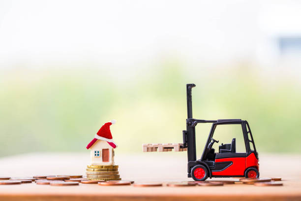 istock tiny home on stack coins with miniature toy forklift machine, over blurred green spring garden background. 1191384611