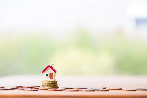 istock selective focus of miniature tiny home with stack coins on wooden floor over blurred green garden background 1191384640