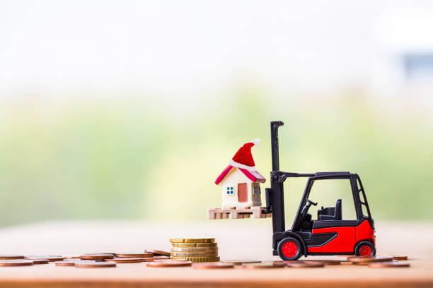 istock tiny home on stack coins with miniature toy forklift machine, over blurred green spring garden background. 1191384770