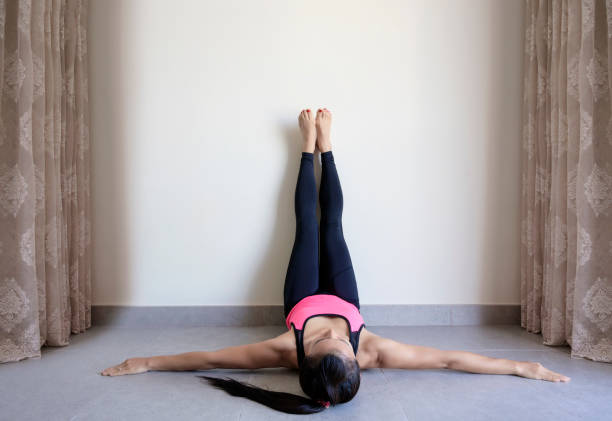 Yoga woman feet up relaxing on wall Yoga woman feet up relaxing in room on wall background pilates stock pictures, royalty-free photos & images