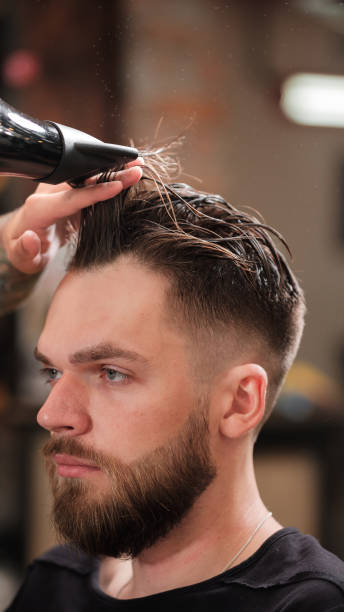 istock Fashionable man with a beard makes hair styling 1191388450