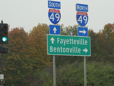 Roadside signs and directions to Fayetteville and Bentonville along Interstate 49 in Arkansas, USA.