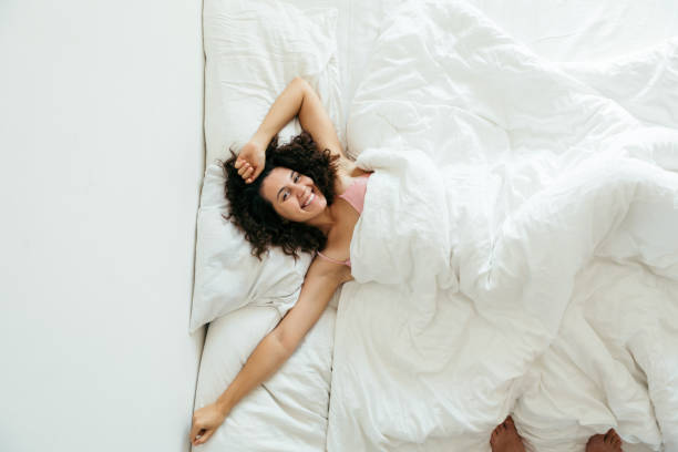 istock young pretty woman in bed with white sheets bright light 1191394110