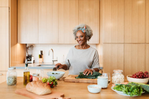istock Smiling retired woman preparing meal in kitchen 1191395056