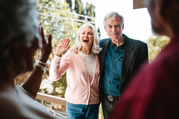 istock Senior couple waving party hosts at front yard 1191395115