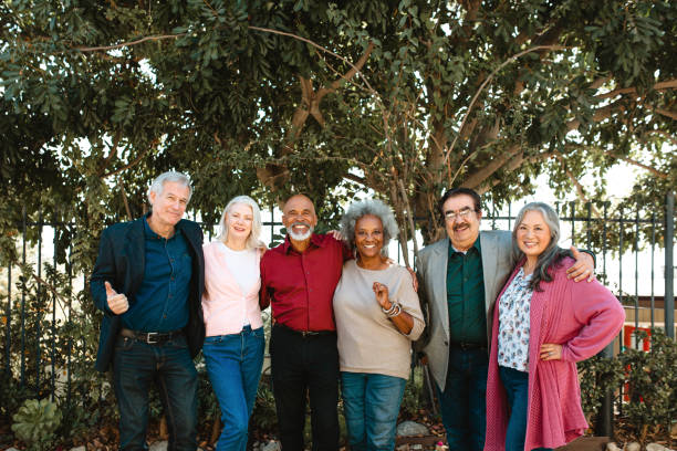 Portrait of smiling multi-ethnic senior friends Portrait of smiling multi-ethnic senior friends standing against trees. Retired men and women are in casuals. They are at enjoying at party. DisruptAgingCollection stock pictures, royalty-free photos & images