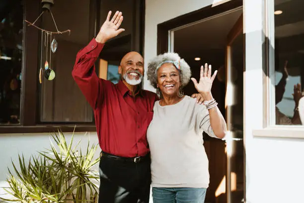 Photo of Smiling retired man standing with arm around wife