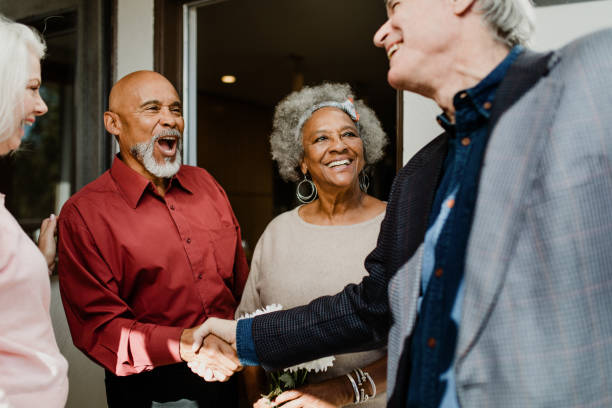 Cheerful men greeting with handshake by women Cheerful men greeting with handshake by women. Senior friends are standing at front yard. They are in casuals. shaved black women stock pictures, royalty-free photos & images