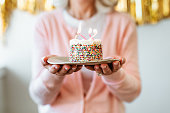 Retired woman holding cake with birthday candles