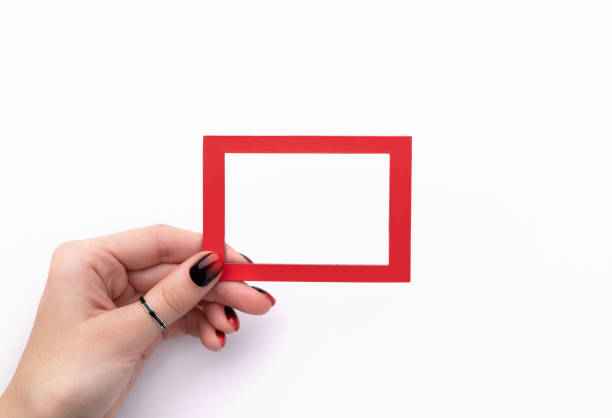 istock Womans hand with manicure holding red frame isolated on white background 1191395577