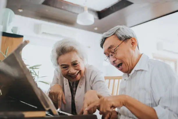 Photo of Thai senior couple enjoy playing paino at home