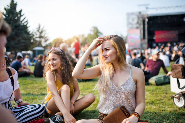 grupo de amigos fêmeas novos que sentam-se na terra no festival de verão. - music festival park friendship summer - fotografias e filmes do acervo