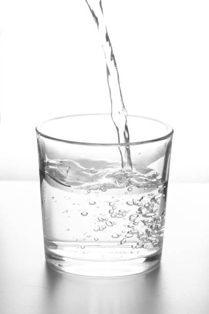 Water Water pouring into glass on white background beaker pour stock pictures, royalty-free photos & images
