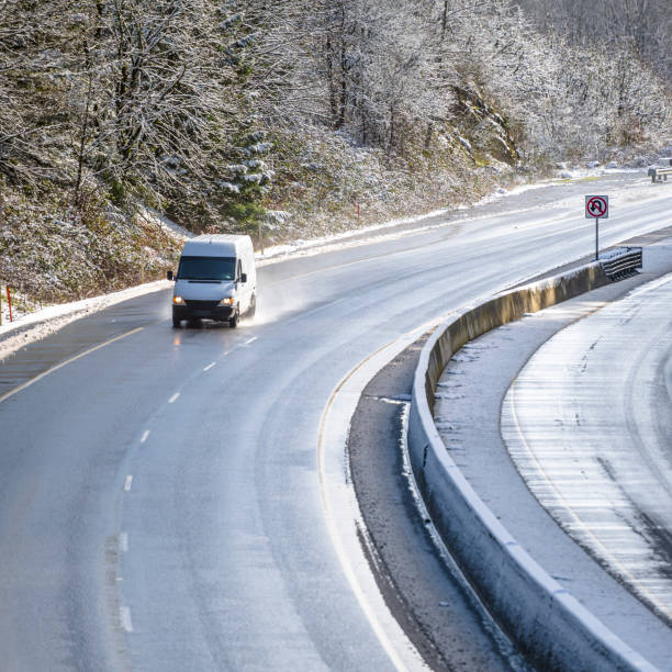 雪の木で濡れた雪の冬の道路を走る白いコンパクトな商業貨物ミニバン - car delivering white mini van ストックフォトと画像