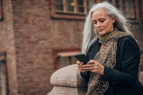 istock Mature lady using mobile on the street 1191399998