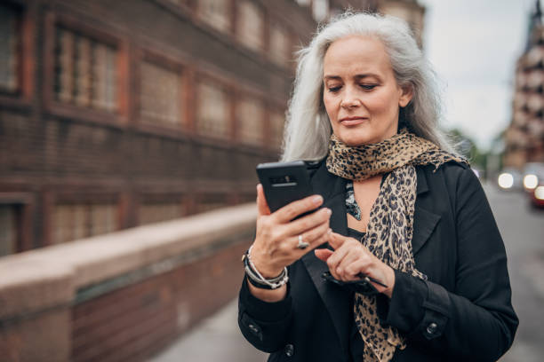 istock Beautiful mature lady using mobile on the street 1191400059