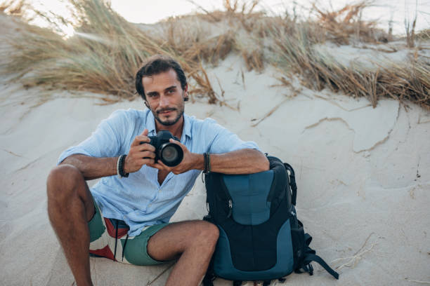 istock Guy photographer with digital camera on the beach 1191403546