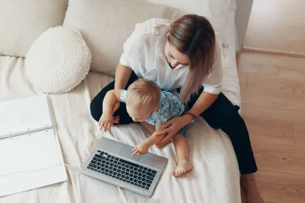 Photo of Modern woman working with child. Multi-tasking, freelance and motherhood concept