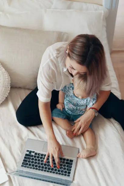 Photo of Modern woman working with child. Multi-tasking, freelance and motherhood concept