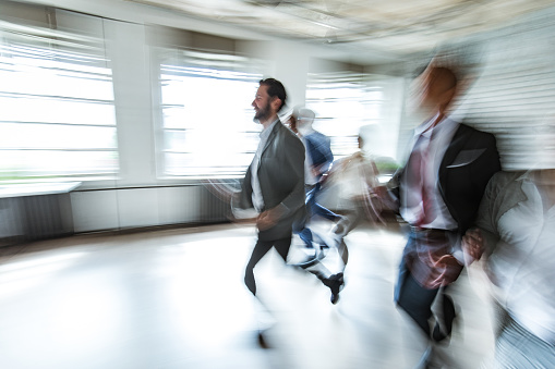 Happy business people running in blurred motion during sports race in the office. Copy space.