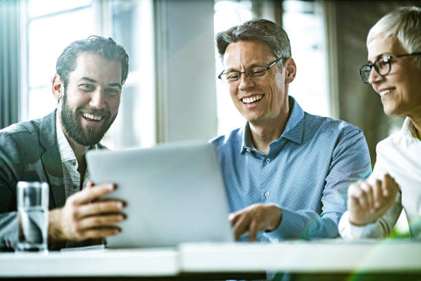 istock Happy business colleagues cooperating while working on laptop in the office. 1191405412