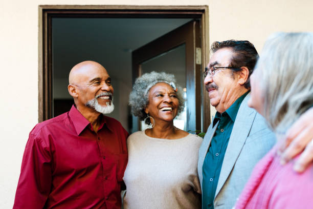 Smiling retired senior friends talking at doorway