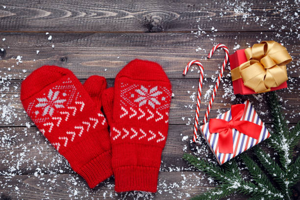 istock Knitted mittens with fir tree branches and gift boxes on wooden table 1191406447