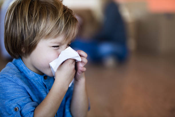 istock Small boy blowing a nose at home. 1191409922
